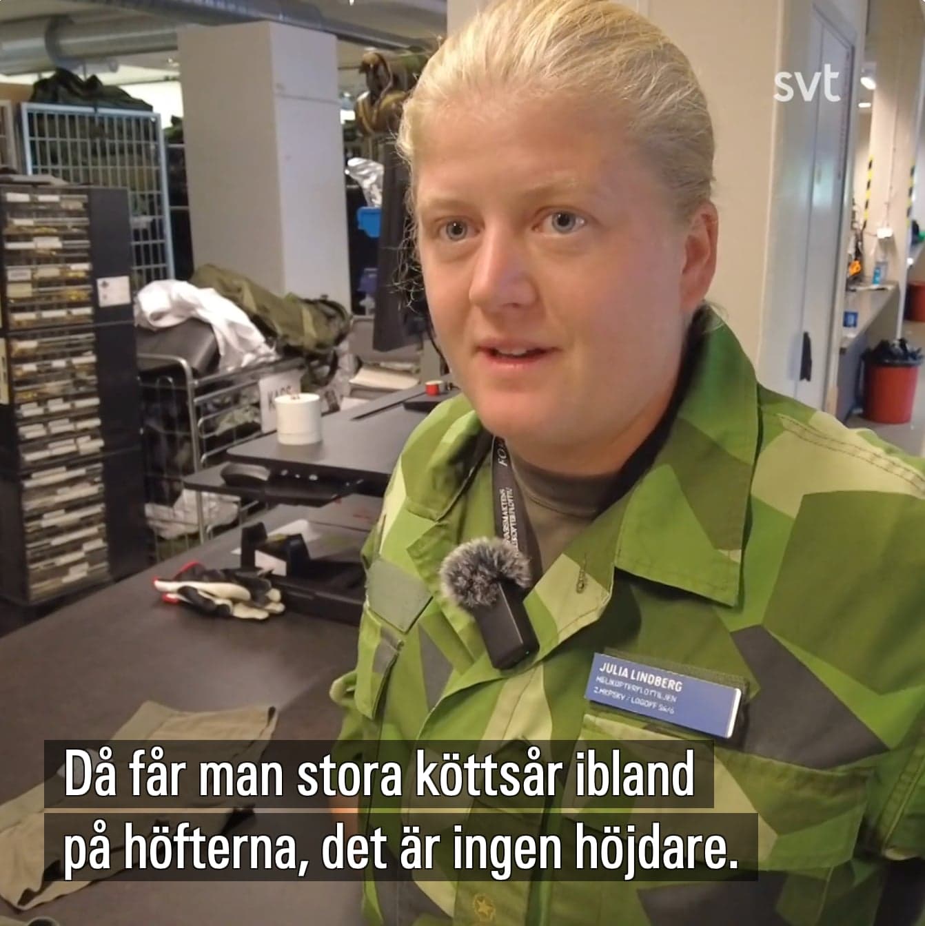 Still from an SVT news video: a soldier in Swedish camouflage being interviewed with a clip microphone in a military clothing store, the Swedish subtitle reading ”Då får man stora köttsår ibland på höfterna”